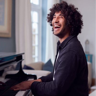 young-man-sitting-at-grand-piano-and-playing-at-ho-2021-08-30-06-14-52-utc-e1697687758956.jpg